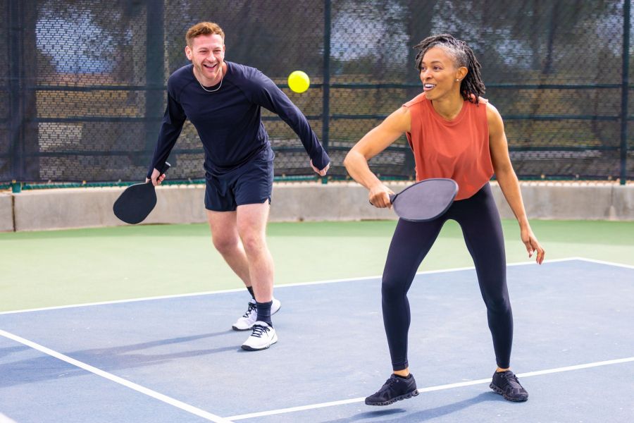 Two people playing tennis in tennis court near Lodges at Fort Mill.