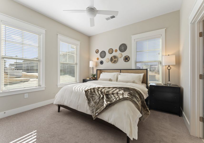 A bedroom with a queen bed, two black nightstands with lamps, and decorative woven wall hangings above the headboard.