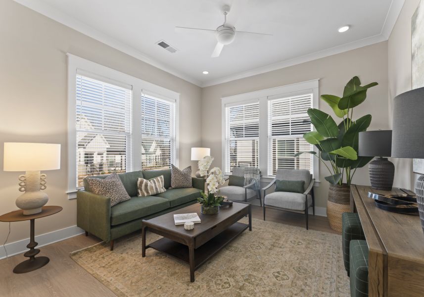 A living room with a green sofa, two gray armchairs, a wooden coffee table, and a large potted plant.